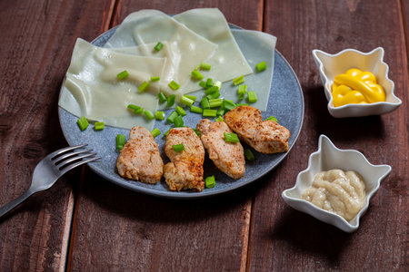 Thin khinkal with meat and greens, onions and different sauces in a plate on a wooden table. horizontal photoの写真素材