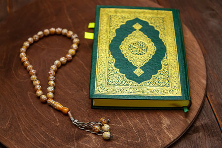 Editorial illustration Koran green cover and rosary beads next to each other on a wooden table. Horizontal photo.の写真素材