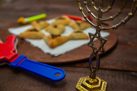 Sweet pastries triangular gomentashi ears of aman for Purim next to a trshchotka and a menorah....