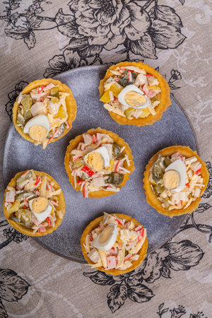 Salad with crabs and pineapples in tartlets on a plate decorated with cilantro on a gray tablecloth. Vertical photo.の写真素材