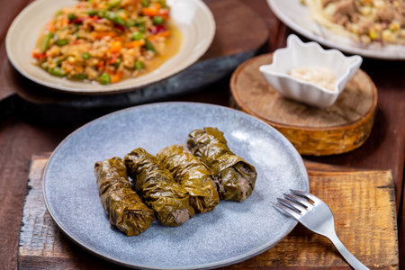 Couscous with vegetables, udon noodles with meat in spices and dolma on a wooden table. Horizontal photo.の写真素材