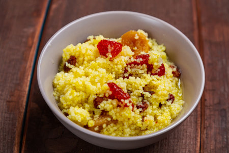 Steamed couscous with nuts and raisins in a plate on the table. Horizontal photo.の写真素材