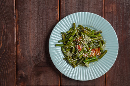 Tzimmes with green beans and tomatoes sprinkled with sesame seeds dish in a plate on the table. Copy space. Horizontal photo.の写真素材
