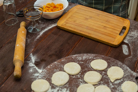 Circles of cookie dough on a table sprinkled with flour next to a rolling pin and other objects. Horizontal photo.の写真素材