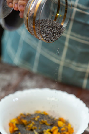 Hands of a Jewish woman pour poppy seeds into the filling on gomentashi for the holiday of Purim. Vertical photo.の写真素材