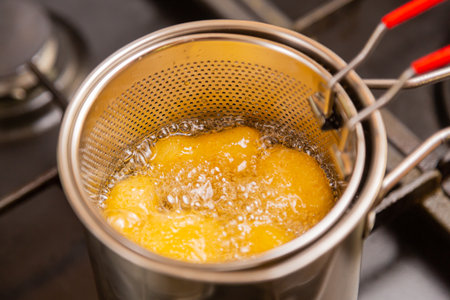 Nuggets in boiling oil in a deep fryer on a stove in a home kitchen. Horizontal photo.の写真素材