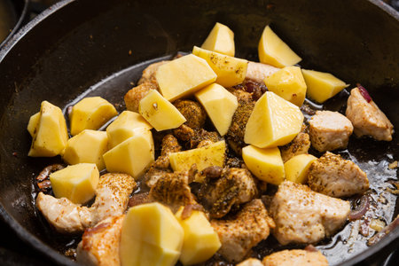 Cholent with potatoes, onions, meat and spices is stewed in a frying pan. Horizontal photo.の写真素材