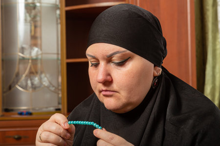 Muslim woman in black hijab reading dhikr before prayer close-up. Horizontal photo.の写真素材