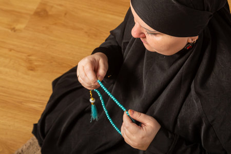 Muslim woman in black hijab reading dhikr before prayer close-up. Horizontal photo.の写真素材