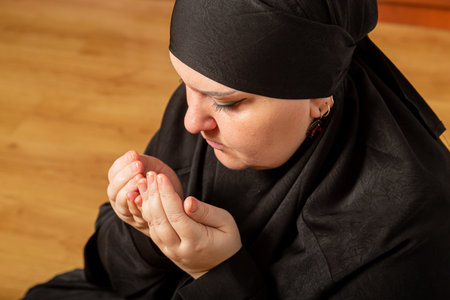 Muslim woman in black hijab performing namaz reading dhikr close-up. Horizontal photo.の写真素材