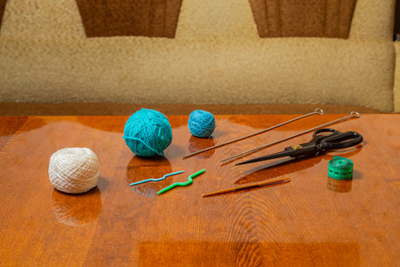 There is a horizontal photo of threads, knitting needles, measuring tape and scissors on the table in the room.の写真素材