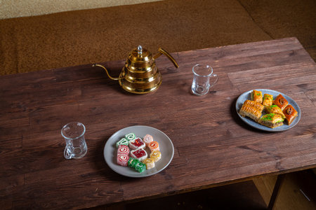 Oriental sweets baklava and lukum on a dark wooden table next to a Turkish teapot and cups Horizontal photo.の写真素材