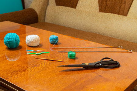 There is a horizontal photo of threads, knitting needles, measuring tape and scissors on the table in the room.の写真素材