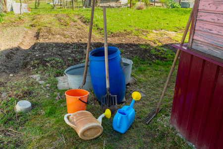 Garden buckets and watering cans of different colors in a suburban area near the wall of the house Horizontal photo.の写真素材