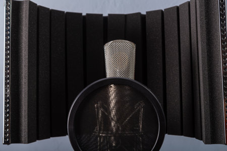 Silver studio microphone with a holder and a pop filter on a gray background. Horizontal photo.の写真素材