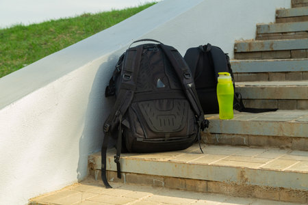 Two photo backpacks and a bottle of water on the steps of a staircase. Horizontal photo.