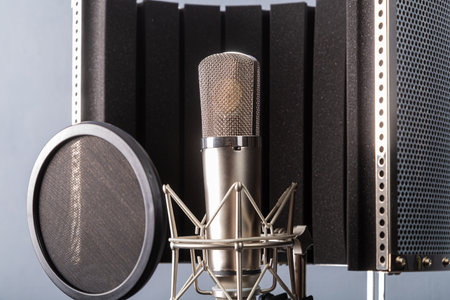 Studio microphone on a holder with a pop filter on a gray background in a recording studio. Horizontal photo.の写真素材