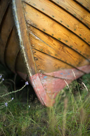 Close up of the keel of an old wooden boat on land with grass growing underneath it.の写真素材