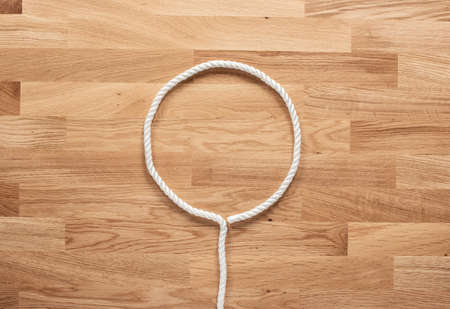 The letter O formed with white rope on a wooden tableの写真素材
