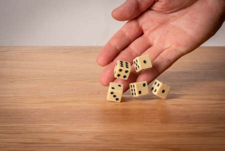 Hand throwing dice in front of a dark background.の写真素材
