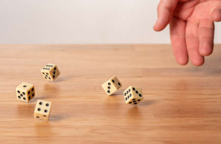 Hand throwing dice in front of a dark background.の写真素材
