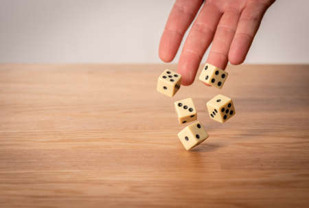 Hand throwing dice in front of a dark background.の写真素材