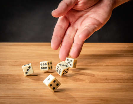 Hand throwing dice in front of a dark background.の写真素材