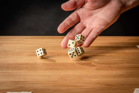 Hand throwing dice in front of a dark background.の写真素材