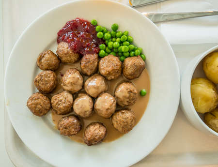 A plate with meat balls, peas, lingonberry jam and potatoes.の写真素材