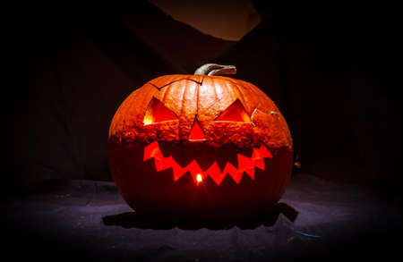 A scary, carved pumpkin effectfully lit from above with lights inside.の写真素材