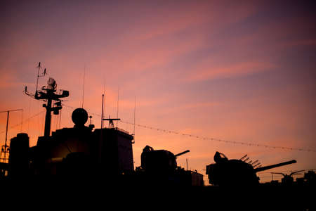 Silhouette of a retired warship against a firey red sunset.