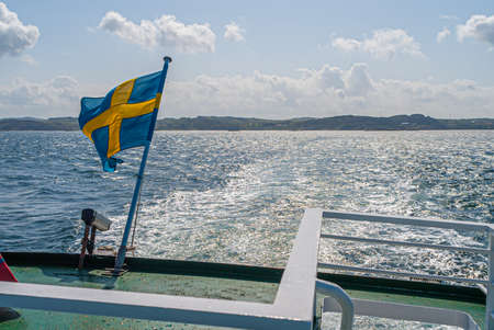 The flag of Sweden flying in the aft mast of a ferry on a sunny summer day.の写真素材