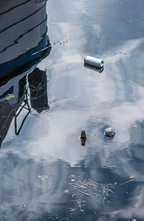 Cans an flasks floating in the water by a boat.の写真素材