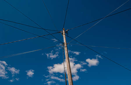 Old wooden power pole with power lines going off in different directions.の写真素材
