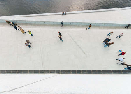 Looking down on pepole walking on a white concrete walkway.