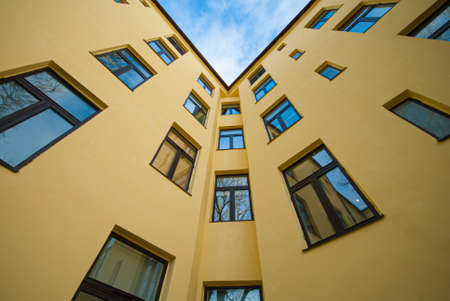 Looking up a yellow apartment building.の写真素材