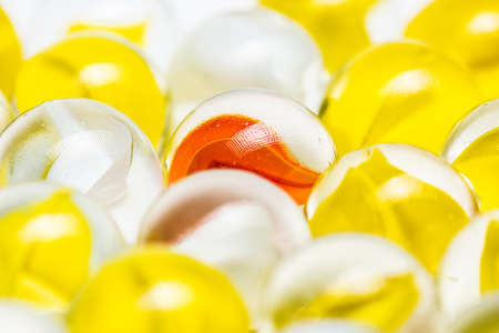 Yellow, white and red glass marbles on a table.
