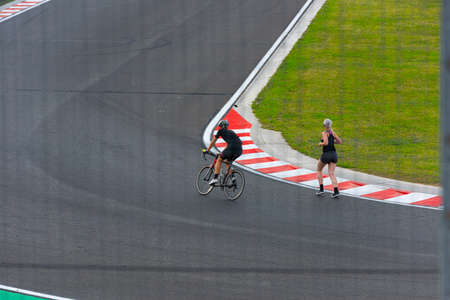Two persons running and cycling on a race track.の写真素材