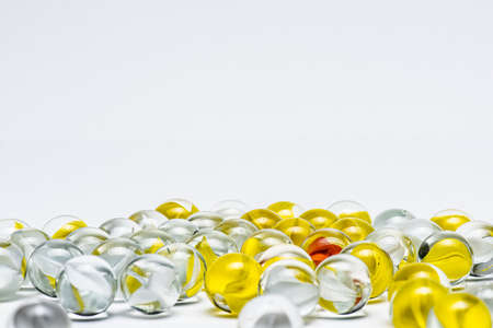 Yellow, white and red glass marbles on a table.の写真素材