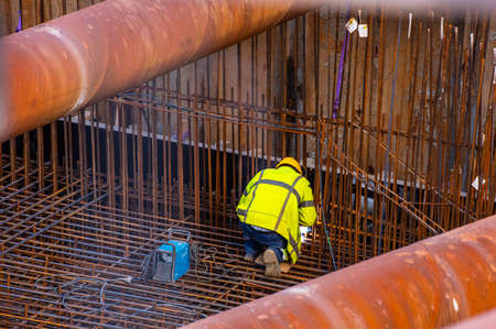 Welding rebar awaiting concrete pouring at a construction site.