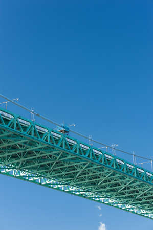 The green painted deck of a suspension bridge seen from underneath.