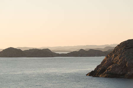 View of steep cliffs by the sea at sunset.