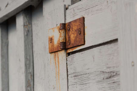 An old, rusty hinge on a white wooden door.の写真素材