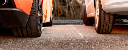 Back wheels of a supercar and a small car in a parking lot.の写真素材