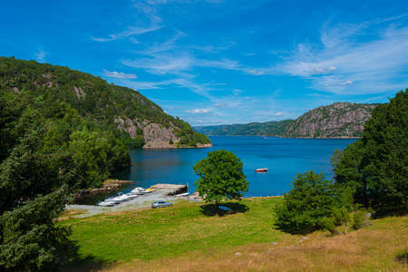 Small boats in a bay by a fjord between steep mountains.