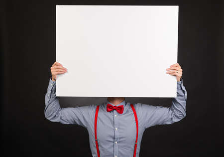Person in blue shirt and red bow tie holding up a white plate.の写真素材