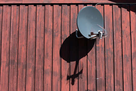 Parabolic antenna on an old wooden wall.の写真素材