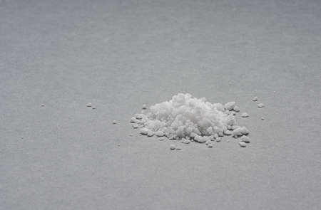 Small pile of salt crystals on grey background.