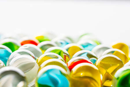 Yellow, green, blue and red glass marbles on a table.の写真素材