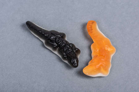 Black and orange wine gum crocodiles on grey background.